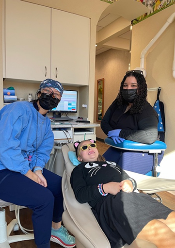 Dental team member and dentist treating dental patient observed by parent