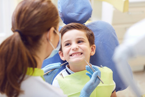 Little boy having teeth examined by female pediatric dentist